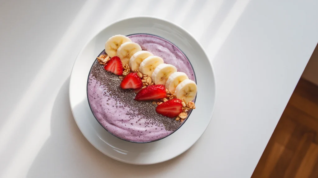 a bowl of oatmeal with sliced banana, berries, nuts, and a drizzle of maple syrup.